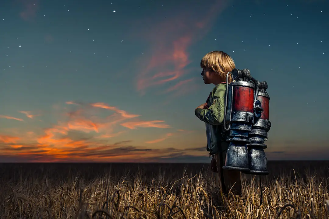 A boy with a jet pack in a field.